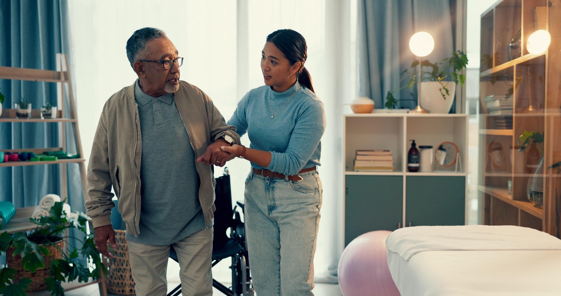 Woman, physiotherapist and senior patient, walking and elderly care for helping movement or balance at clinic. Female nurse, physio and caregiver, assisting and mature man or person with a disability